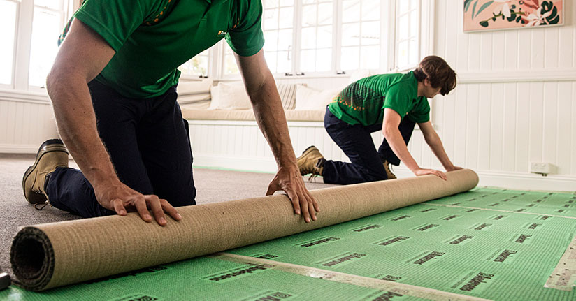 Two Andersens installers roll out a new carpet in a home