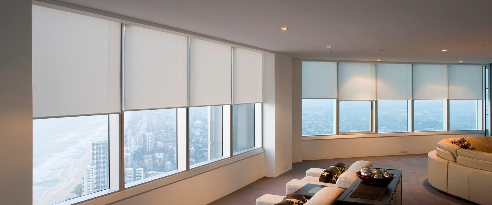Roller blinds lowered across a wall of windows in a living room