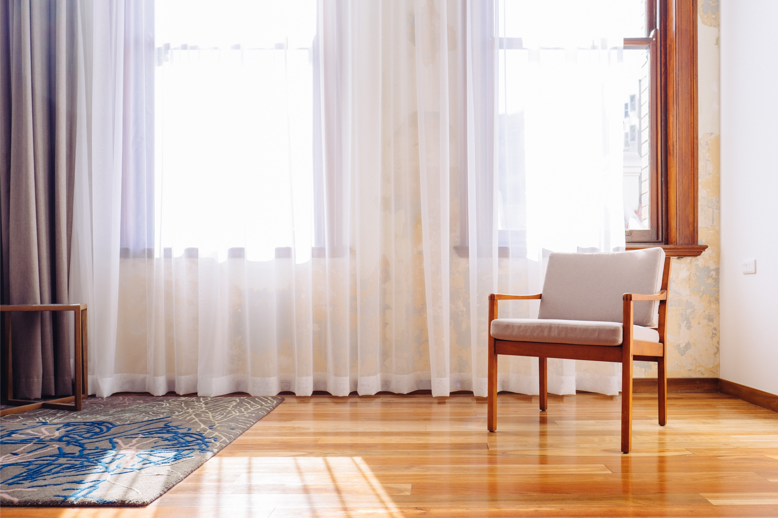 Sheer curtains drawn across a window in a living room with a timber floor