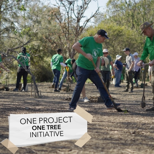 Volunteers in Andersens shirts planting trees beside a One Project One Tree sign