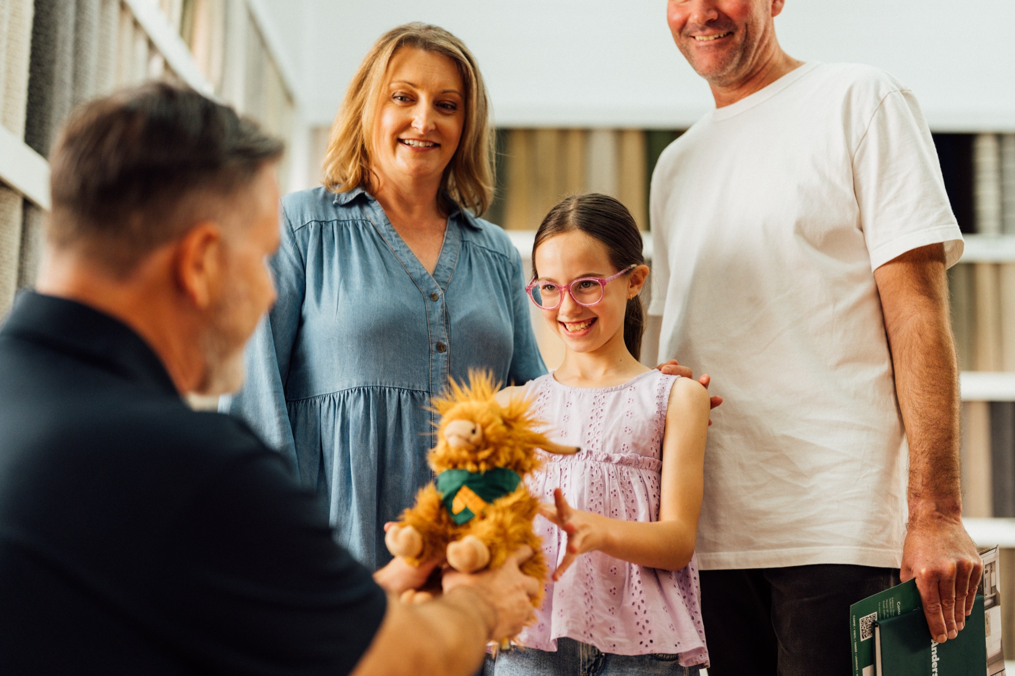 An Andersens staff member handing the Andi mascot to a family in the showroom
