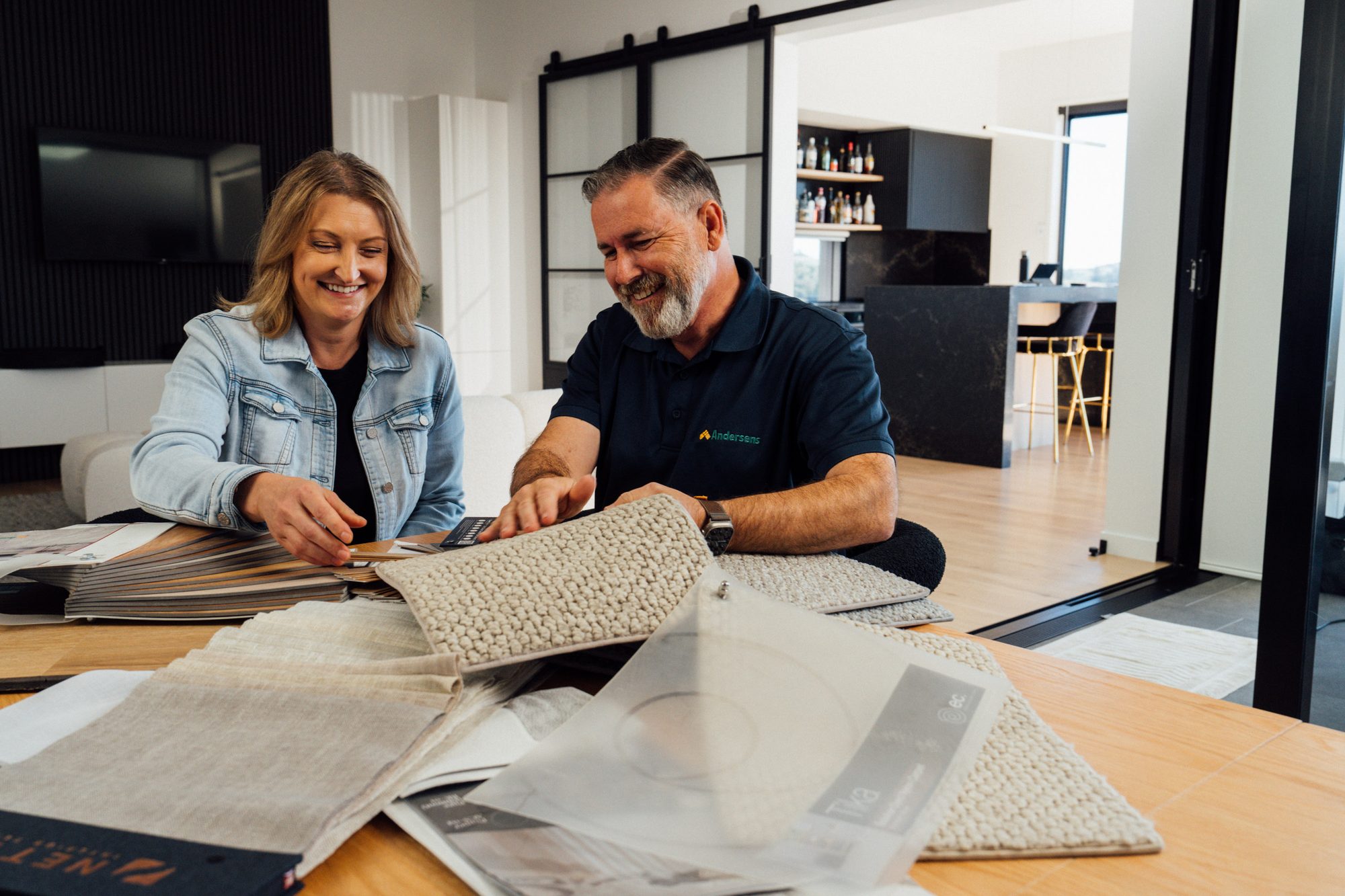 An Andersens consultant and a customer looking through carpet samples spread across her dining table