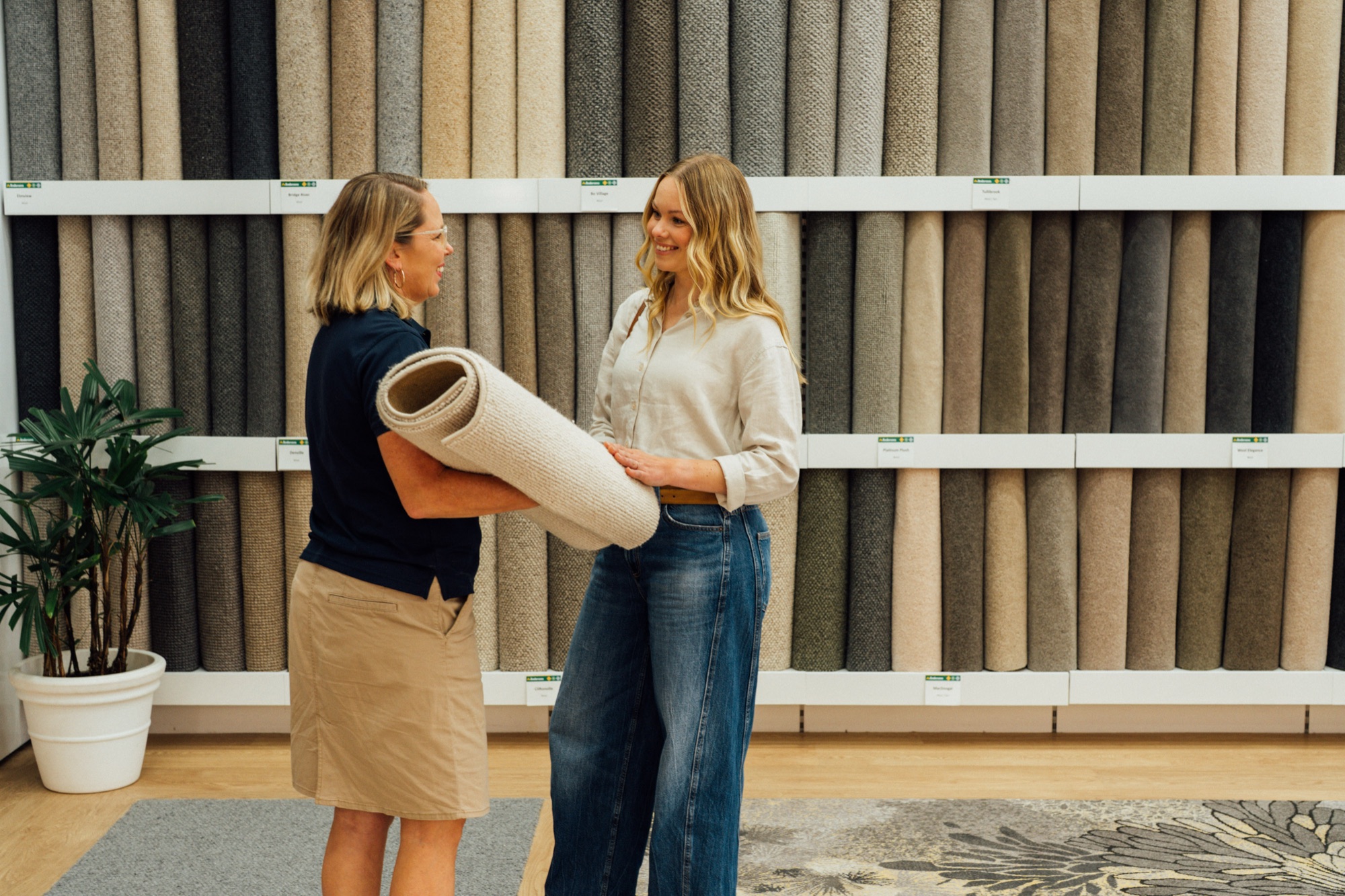 A customer and an Andersens consultant looking along a wall of carpet samples