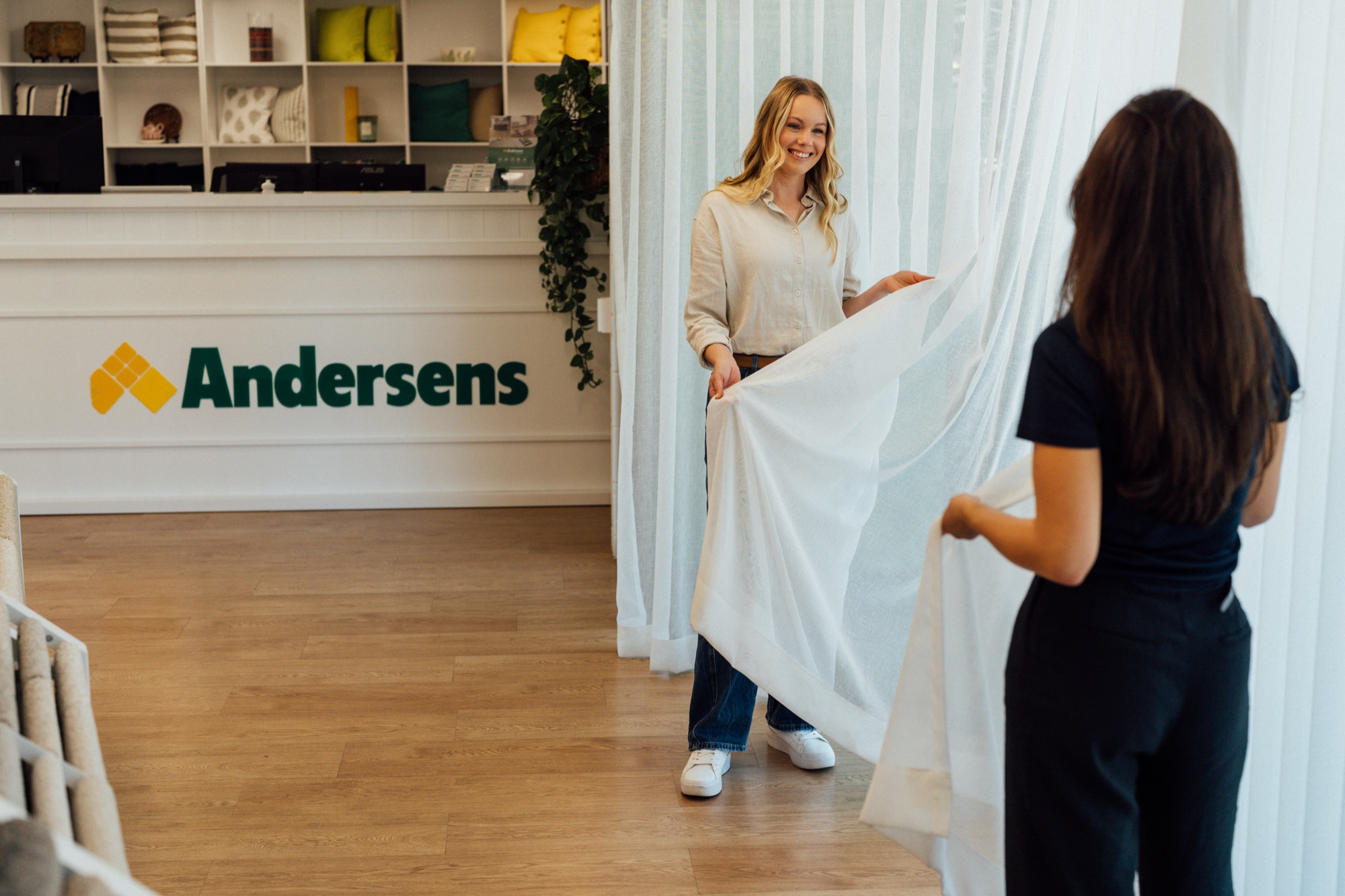 An Andersens consultant holding curtain fabric in front of the showroom counter