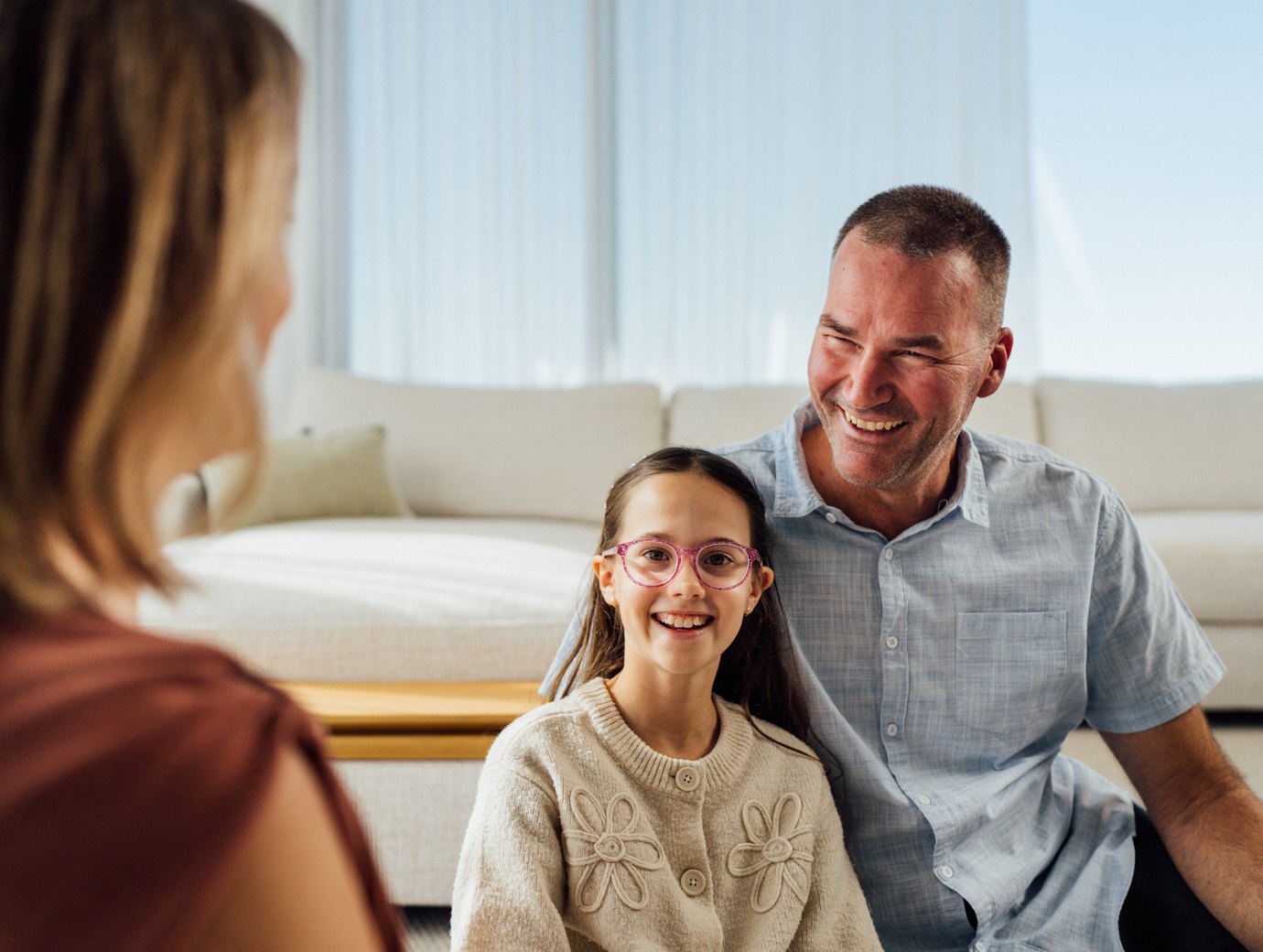 A family sitting together in a living room with sheer curtains behind them
