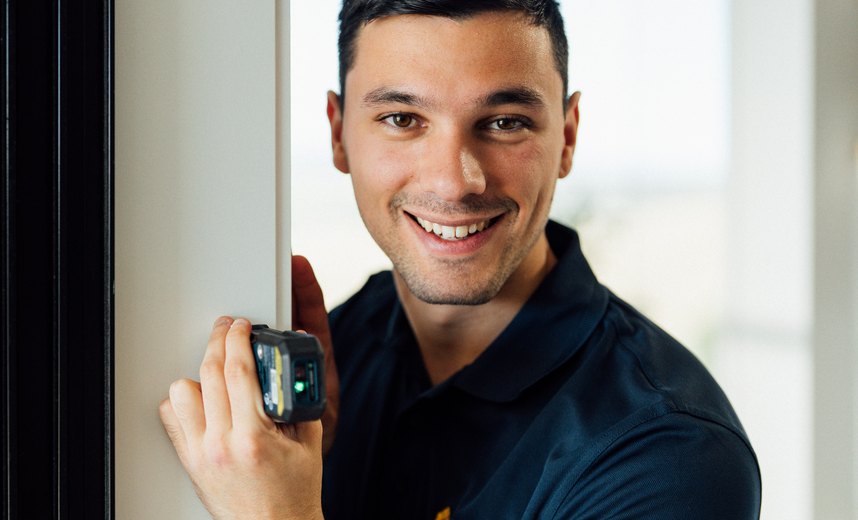 An Andersens consultant using a laser measure at a window