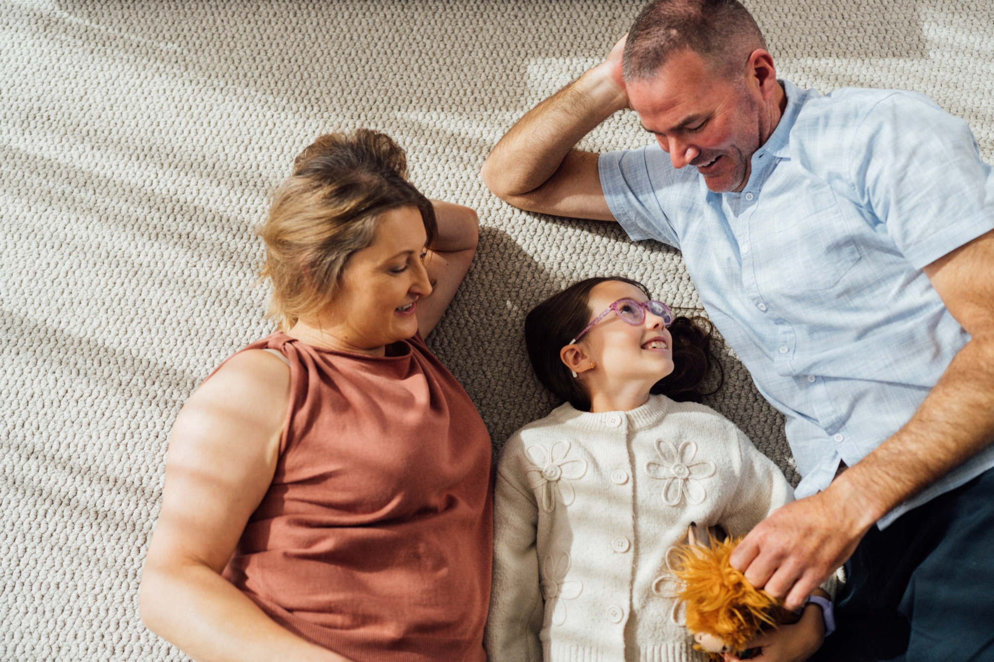 A family lying together on the carpet of their living room