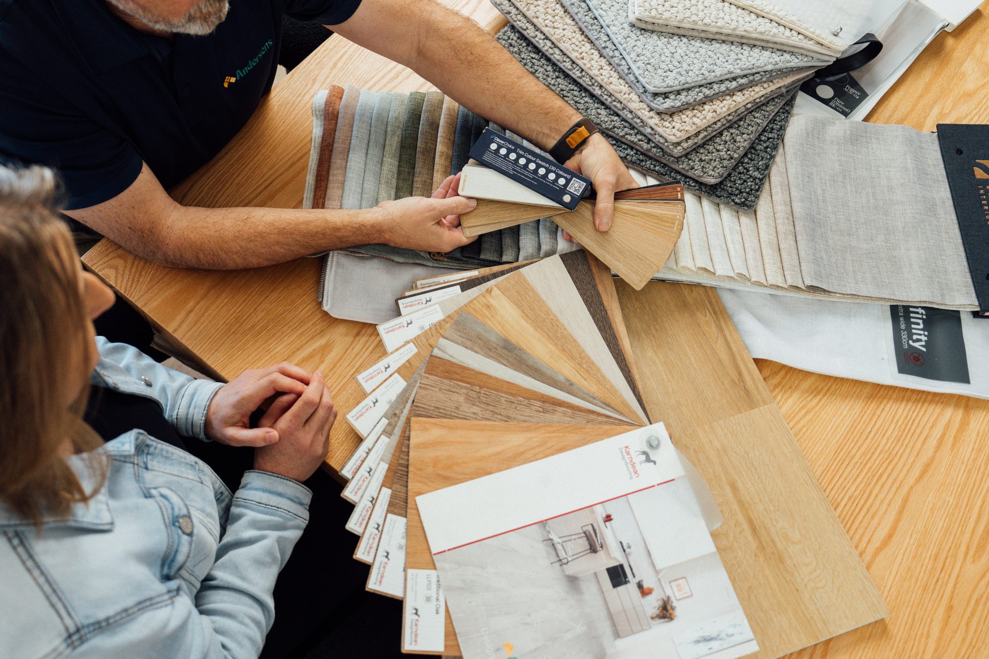 Timber-look and carpet samples fanned across a dining table while a consultant holds one up