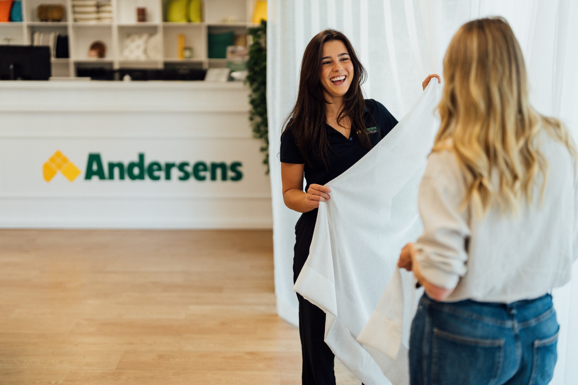 An Andersens consultant showing sheer curtain fabric to a customer in the showroom