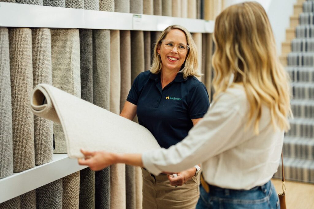 Andersens team member showing a carpet sample in a showroom