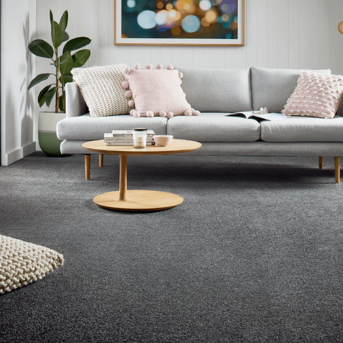 Dark grey carpet in a living room with a pale sofa and a round timber coffee table