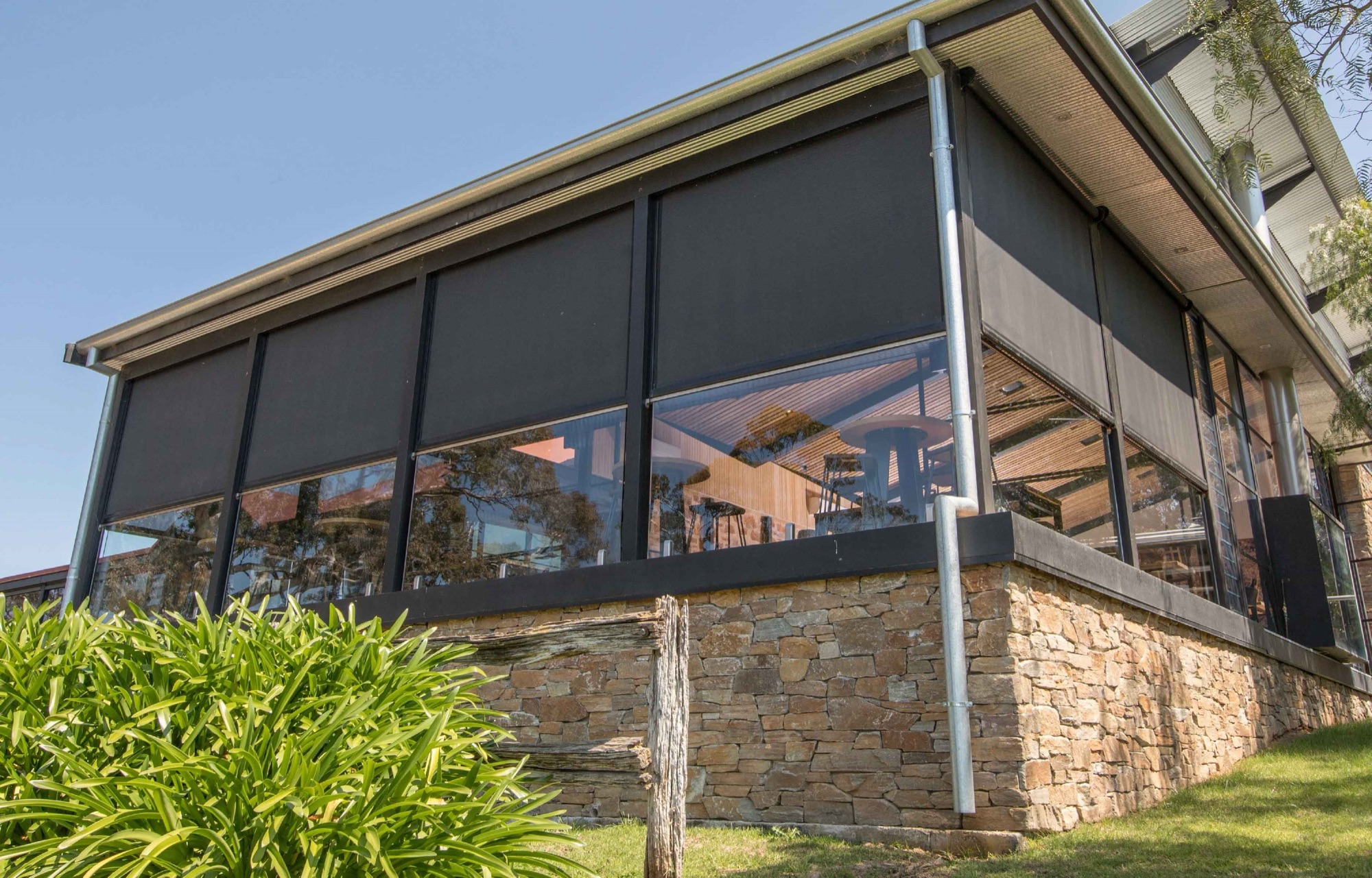 Exterior screens lowered part way down a glazed room, leaving the lower windows clear