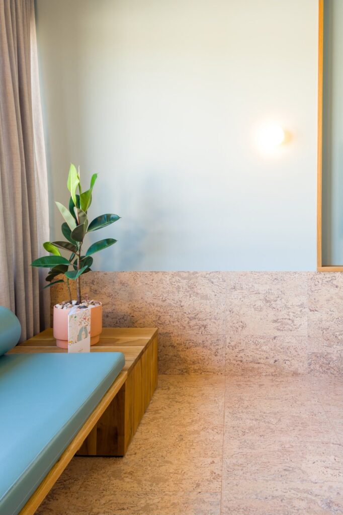 A cork floor and cork wall in a room with a bench seat and a potted plant