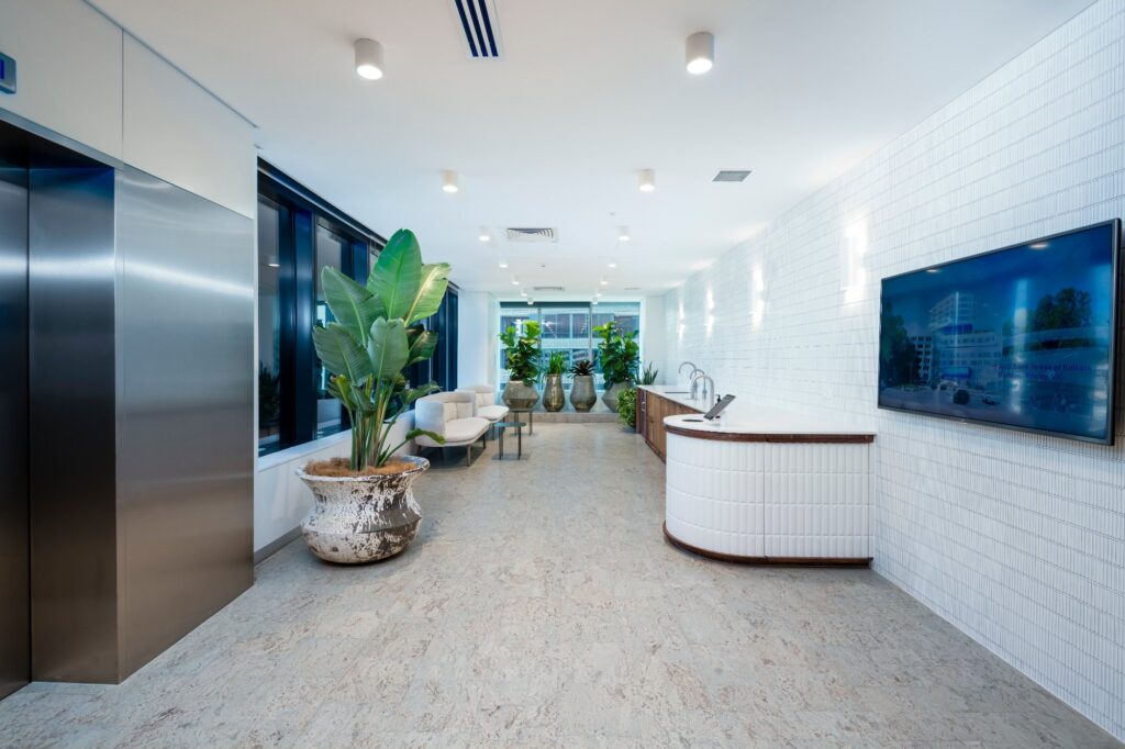A cork floor running the length of a light filled open foyer with planting and seating