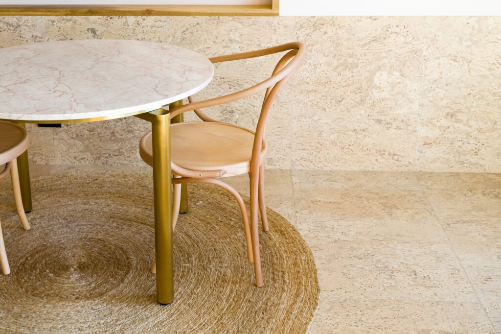 A cork floor in a cafe setting with a round table and a bentwood chair on a woven rug