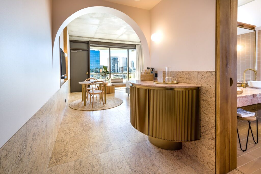 A cork floor running through a bathroom and living area under an arched opening