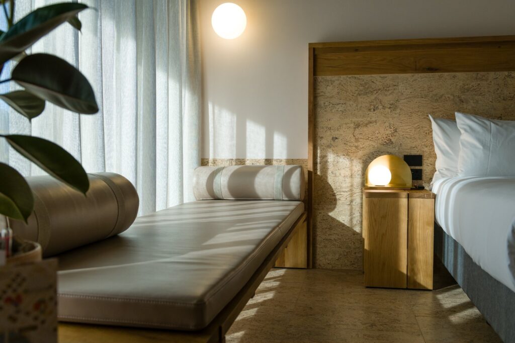 A cork floor in a bedroom with a daybed, a bedside lamp and morning light across the floor