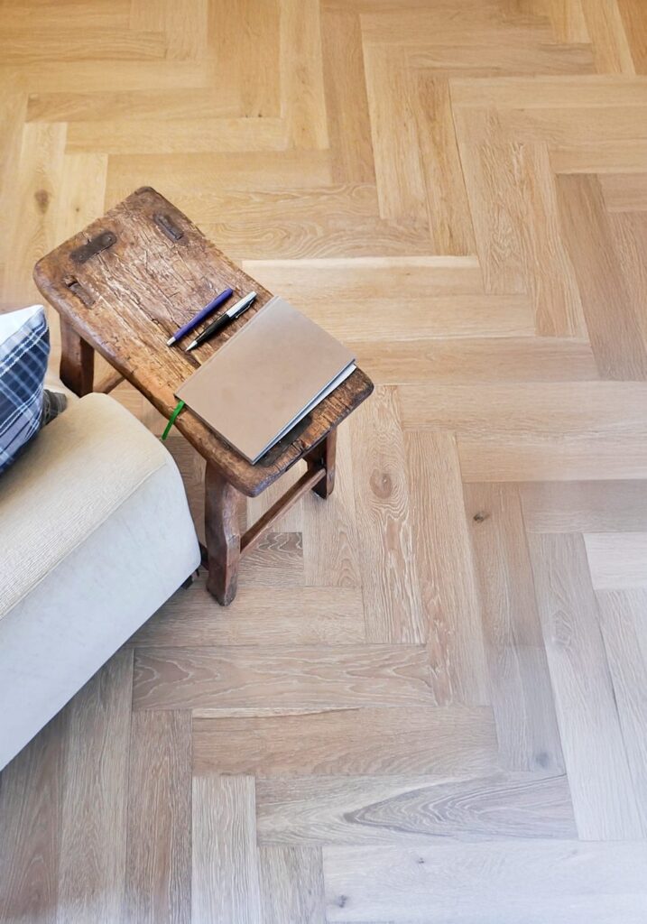 A close view of a herringbone timber-look floor beside a timber stool