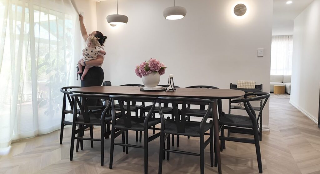 A family at home in a dining room with a herringbone timber-look floor and sheer curtains