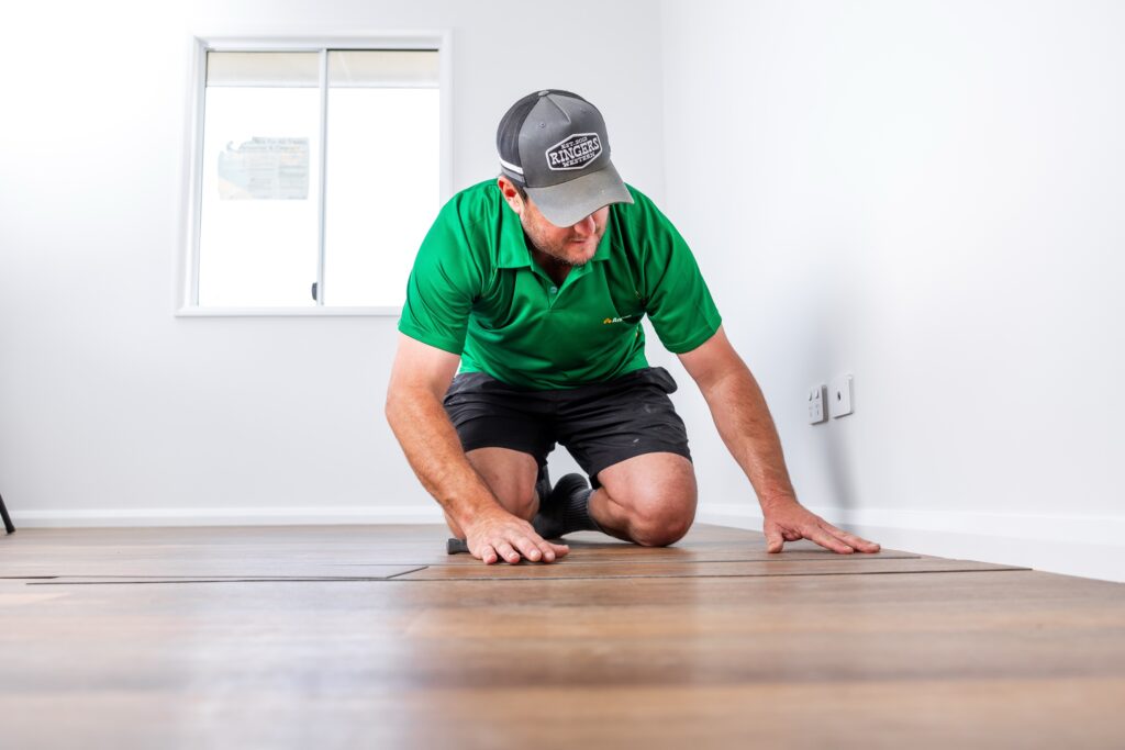 An installer laying new flooring in an empty room