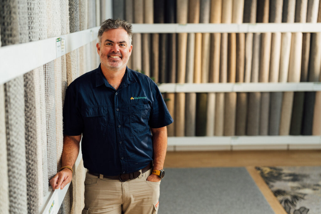 An Andersens Stafford team member standing beside the wall of carpet samples